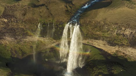 Landscape-of-Iceland,-Aerial-View-of-Seljalandsfoss-Waterfall-in-Summer-Season,-Rainbow-Above-Flowing-Water,-Drone-Shot