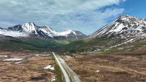 Majestic-Orskog-mountain-valley-area-between-Alesund-and-Vestnes-in-Norway---Rising-spring-aerial-with-road-and-tall-snow-capped-mountain-peaks