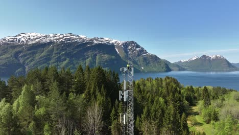 Arbeiter-Auf-Der-Spitze-Eines-Mobilfunkmastes-Mit-Norwegischem-Fjord-Und-Bergkulisse-Im-Hintergrund---Sommerantenne