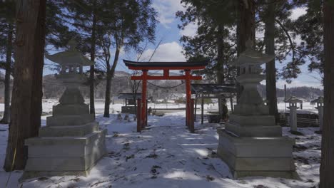 Amidst-a-small-forest-sanctuary,-a-traditional-Japanese-gate-reveals-a-stunning-winter-spectacle-as-it-opens-up-to-reveal-the-vast-and-awe-inspiring-landscape-of-snow-and-mountains-in-Hakuba