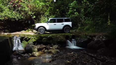 Conduciendo-Ford-Bronco-Sobre-Lastre-En-El-Bosque,-Sobre-Un-Río