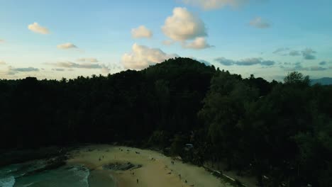 4K-Cinematic-nature-aerial-footage-of-a-drone-flying-over-the-beautiful-beach-of-Surin-in-Phuket,-Thailand-during-sunset