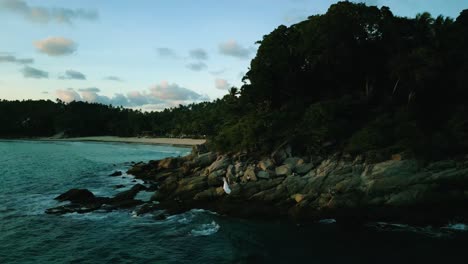 4K-Cinematic-nature-aerial-footage-of-a-drone-flying-over-the-beautiful-beach-of-Surin-in-Phuket,-Thailand-during-sunset