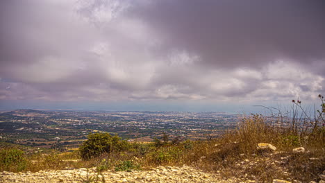 Tiro-De-ángulo-Alto-Sobre-La-Ciudad-Costera-Desde-El-Punto-De-Vista-De-La-Estación-De-Radio-En-Chipre-A-Lo-Largo-De-Las-Laderas-De-Una-Montaña-En-Un-Día-Nublado-En-Timelapse