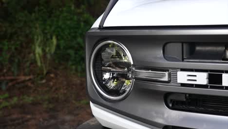 Ford-Bronco-Auf-Ballast-Im-Wald-Fahren,-Autogrill,-Autolichter