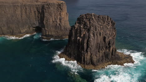 Roque-Partido,-Gran-Canaria:-aerial-view-at-close-range-and-in-orbit-of-the-rock-formation-called-Roque-Partido-on-the-island-of-Gran-Canaria-and-on-a-sunny-day