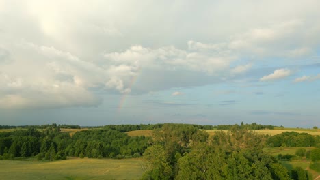 Wunderschöne-Panoramische-Weiße-Wolken,-Felder-Und-Entfernter-Regenbogen,-Luftaufnahmen