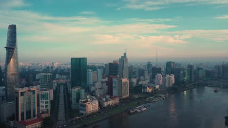 Orbit-drone-shot-over-Saigon-River-and-Ho-Chi-Minh-City-Skyline-at-dawn-featuring-all-key-buildings