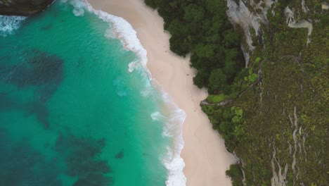 top-view-of-the-turquoise-water-waves-crashing-the-white-sand-of-Kelingking-beach-know-also-as-Cap-de-T-rex---Nusa-Penida,-Indonesia