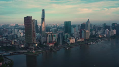 Fly-in-drone-shot-over-Saigon-River-towards-Ho-Chi-Minh-City-Skyline-at-dawn-featuring-all-key-buildings