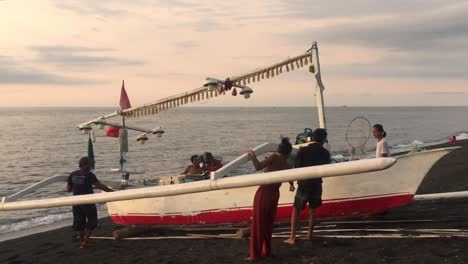 Barco-Pesquero-Tradicional-En-Indonesia-Siendo-Empujado-Hacia-El-Océano-Por-La-Familia-De-Pescadores-En-El-Norte-De-Bali.