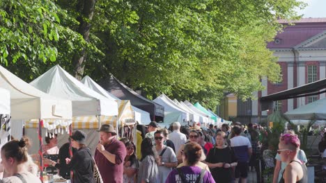 Mucha-Gente-Caminando-Por-Los-Puestos-Del-Mercado-En-Una-Soleada-Tarde-De-Verano.