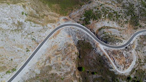 Drone-shot-flying-over-a-curvy-road-in-the-terrain-landscape-of-Andalusia-in-Spain