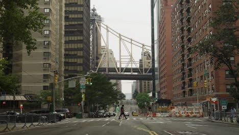 Los-Peatones-Cruzan-La-Calle-En-La-Ciudad-De-Nueva-York-Con-El-Puente-Sobre-La-Cabeza.