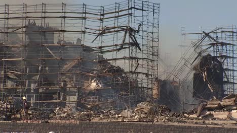 Un-Bombero-Solitario-Camina-Junto-A-Un-Complejo-De-Apartamentos-Incendiado-24-Horas-Después-De-La-Primera-Respuesta