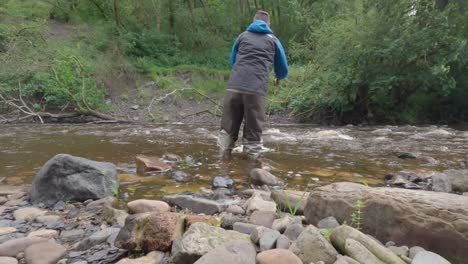 Niedrige-Statische-Aufnahme-Eines-Mannes,-Der-In-Einem-Kleinen-Abgelegenen-Fluss-In-Schottland-Watet-Und-Fliegenfischen-Geht