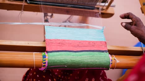 Scene-from-above-in-which-a-Kutch-woman-artisan-is-working-with-both-her-hands-to-make-shopping-bags-by-sewing-and-drawing-plastic-laces