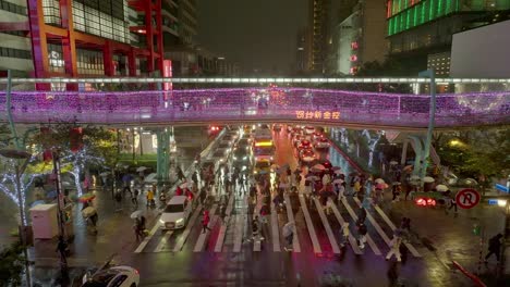 Crowd-of-people-with-umbrella-crossing-street-in-Taipei-at-night-during-Christmas-season---aerial-view