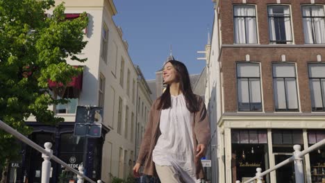 Woman-in-white-tunic-and-brown-clothes-strolls-happy-walking-through-historic-shopping-district