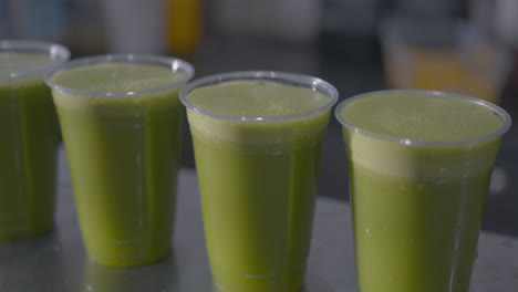 Close-Up-Dolly-of-of-a-Row-of-Green-Juices-on-a-Counter