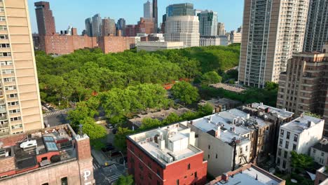Aerial-flyover-residential-area-in-Brooklyn-Heights-with-idyllic-green-park-area-and-high-rise-buildings-in-background-at-sunny-day---New-York-City,-USA