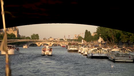 Tour-boat-barges-on-the-Seine-river-going-under-bridge,-Forward-shot