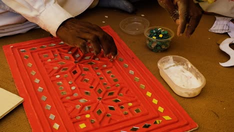 close-up-of-the-scene-in-front-of-the-horn-in-which-the-Kutchi-craftsman-is-pasting-abhlas-and-chandeliers-into-his-mudwork-paintings