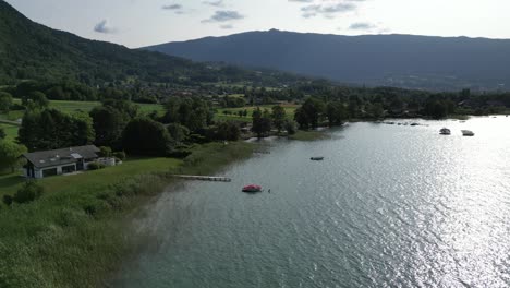 Shore-Aerial-shot-of-Lake-Annecy-France-sunset,-ripples-on-water