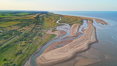 Discover-the-idyllic-charm-of-a-golden-hour-coastal-scene-through-breathtaking-aerial-drone-footage:-estuary,-sandbanks,-ocean,-and-marshlands