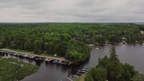 Aerial-Drone-View-Of-Lake-With-Moorings-Surrounded-By-Thicket-Forest