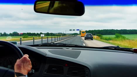 4k-60fps-Hände-Einer-älteren-Frau,-Die-Ein-Auto-Auf-Der-Autobahn-Fährt-Und-An-Einem-Gelben-Bus-Vorbeifährt-–-Handaufnahme