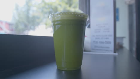 Close-Up-Dolly-Forward-of-a-Green-Juice-in-a-Cup-by-a-Window