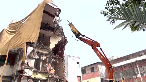 Excavadora-Con-Martillo-Demoliendo-Un-Pequeño-Edificio-En-La-Ciudad-India