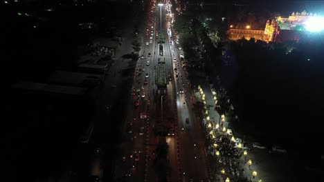 Por-La-Noche,-Rath-Yatra-Del-Señor-Jagannath-Corre-En-La-Carretera-En-La-Que-Se-Ve-El-Tráfico-Regular-En-Los-Carriles-Restantes-De-La-Carretera-En-La-Que-Se-Mueven-Más-Bicicletas,-Automóviles,-Autobuses-Y-Camiones.