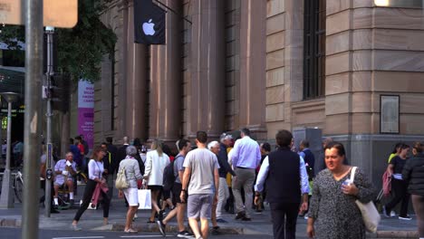 Large-swarm-of-people-crossing-the-road-at-the-corner-of-Queen-and-Edward-street-during-rush-hours,-Brisbane-Apple-flagship-store-in-heritage-listed-MacArthur-Chambers-in-the-background,-static-shot