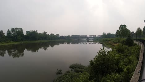 Flusszeitraffer-An-Einem-Nebligen,-Rauchigen-Tag-Mit-Brücke-Im-Hintergrund