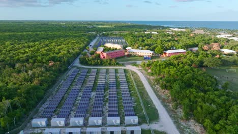 Aerial-flyover-solar-panel-farm-producing-green-energy-for-hotel-resort-in-Punta-Cana-in-summer---Caribbean-Sea-in-background---forward-flight