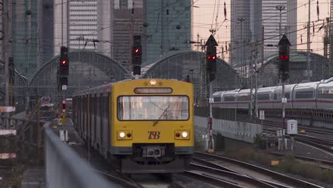 Yellow-german-S-Bahn-Train-leaves-the-railway-station-of-Frankfurt,-skyline
