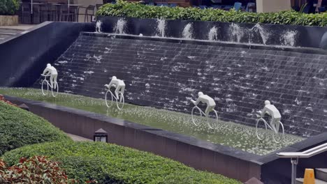 Die-Skulptur-Von-Fahrradfahrern-In-Einem-Pool-Neben-Einer-Wasserwand-In-Einem-Beliebten-Einkaufszentrum-In-Cebu-City-Ist-Ein-Beliebter-Unterhaltungs--Und-Selfie-Hintergrund-Für-Besucher-Und-Käufer