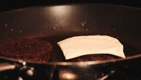Vegane-Burger-Auf-Pflanzlicher-Basis-Mit-Käse,-Der-In-Der-Heißen-Pfanne-Von-Hand-Darauf-Geschichtet-Wird