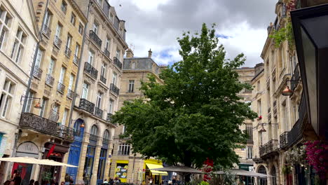 Tilt-up-pov-in-city-of-Bordeaux-with-eating-people-outdoors-in-restaurant-during-cloudy-day---historic-buildings-in-old-town,-France