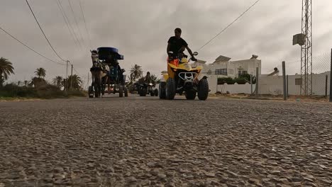 Vorderansicht-Von-ATVs-Oder-Quads,-Die-Kutschen-Mit-Touristen-überholen,-Die-Von-Pferden-Durch-Die-Straßen-Von-Djerba-In-Tunesien-Gezogen-Werden