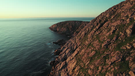 Drohne-Folgt-Der-Küste-In-Einer-Wunderschönen-Sonnenuntergangsatmosphäre-In-Nordnorwegen,-Norwegischer-Klippenlandschaft,-Nordkap,-Skandinavien