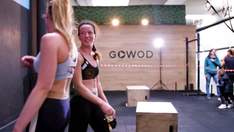 Two-female-athletes-in-the-gym-greet-each-other-by-tapping-their-fists-together-and-share-a-smile,-exuding-a-sense-of-camaraderie-and-mutual-respect