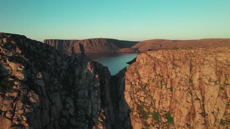 Drone-Approaching-a-Cliff-Hole-in-the-Coastline-in-a-Beautiful-Sunset-Atmosphere-in-Northern-Norway,-Norwegian-Cliff-Landscape,-North-Cape,-Scandinavia