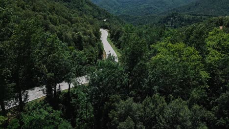 Vista-De-Pájaro-De-Una-Carretera-Que-Atraviesa-Un-Bosque-Y-Una-Región-Montañosa