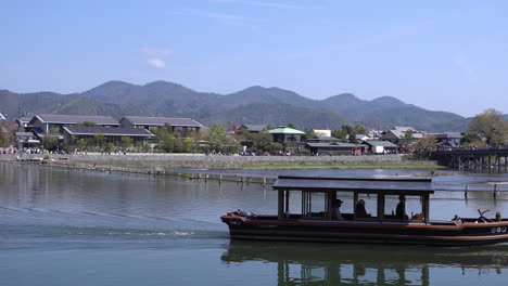 KYOTO,-JAPAN---April-4,-2023:-Boats-in-Katsura-River-in-Arashiyama-district-with-cherry-blossom-in-spring-time