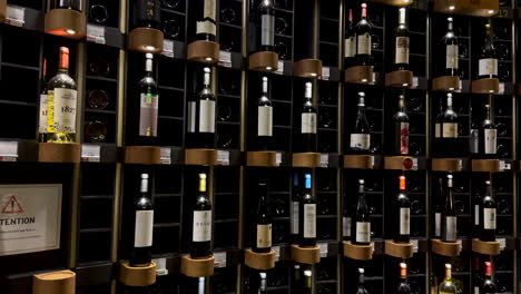 Primer-Plano-Panorámico-De-La-Pared-De-Diferentes-Botellas-De-Vino-En-El-Museo-Del-Vino-Cite-Du-Vin,-Burdeos