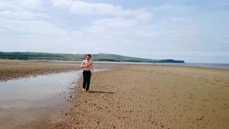 Orbital-footage-of-a-young-man-without-a-shirt-walking-alone-on-a-beach