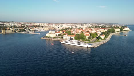 Beautiful-wide-aerial-panorama-over-Zadar-Croatia,-while-luxury-cruise-ship-docked-near-Greetings-to-the-Sun,-blue-Adriatic-Sea